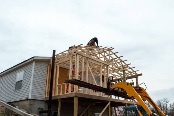 Unidentified carpenters work on the new roof, aided by some heavy equipment. Construction work is progressing nicely